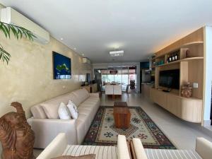 a living room with a white couch and a table at Casa de Praia Pé na Areia Boiçucanga 6 in São Sebastião
