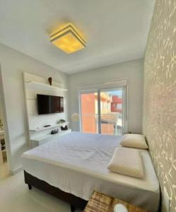 a bedroom with a large bed and a tv at Casa de Praia Pé na Areia Boiçucanga 6 in São Sebastião