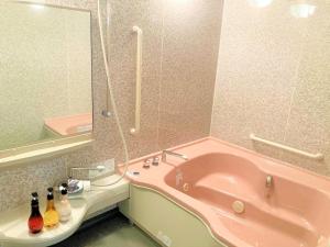 La salle de bains est pourvue d'une baignoire rose et d'un miroir. dans l'établissement Shirakaba no mori Cottage - Vacation STAY 60815v, à Abashiri