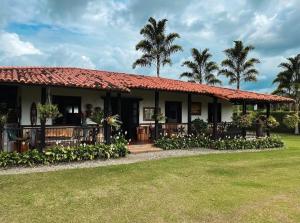 una casa con un prato verde davanti di Hermosa Casa Campestre en Montenegro-Quindío a Montenegro