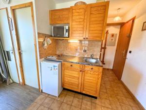 a small kitchen with wooden cabinets and a white refrigerator at Studio confortable pour 2 personnes, centre village, proche téléski - Saint Martin de Belleville - FR-1-452-319 in Saint-Martin-de-Belleville