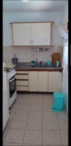 Una cocina con gabinetes blancos, un fregadero y una estufa. en Cabaña en gesell, en Villa Gesell