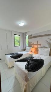 a bedroom with two beds with black pillows on them at ILOA Apto 02 quartos H in Barra de São Miguel