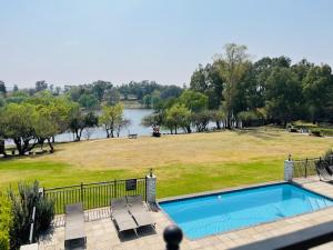 a swimming pool with a view of a park and a lake at Pont de Val Studio Apartment in Parys