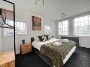 a bedroom with a large bed and windows at Central duplex Apt in Leamington Spa in Leamington Spa