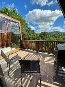 a deck with two chairs and a grill at Reserva Linha Bonita - Chalés Românticos in Gramado