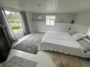 a white bedroom with a large bed and a window at Traumhaus mit Seegrundstück in Holmsjö