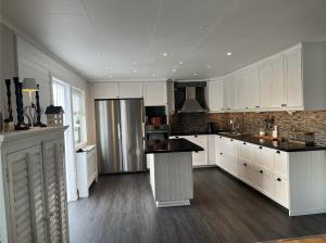 a kitchen with white cabinets and a stainless steel refrigerator at Traumhaus mit Seegrundstück in Holmsjö