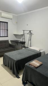 zwei Betten in einem Zimmer mit einer Couch und einem Klavier in der Unterkunft Lar Aconchego in Palmas