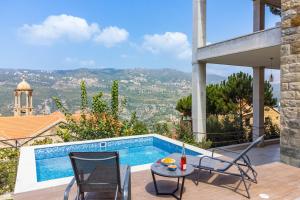 Al QannābahにあるBeit Salima - 3 Bedroom House with Pool & Terraceのスイミングプール、椅子2脚、テーブル1台が備わる家