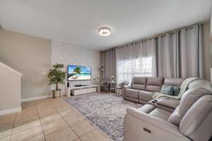 a living room with a couch and a tv at 5BR Paradise Palms Townhome POOL by Disney in Kissimmee