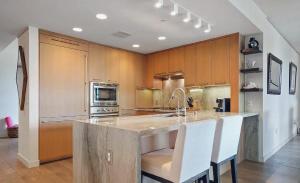 ロサンゼルスにあるSuperb Two Bedroom Condo in Santa Monicaの白い椅子付きの大きな島のあるキッチン