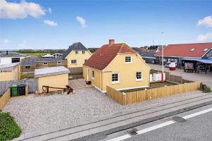 a yellow house with a fence next to a street at 70240-Ulfborg-Vesterhavsgade-12 in Thorsminde