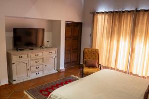 a bedroom with a bed and a television and a chair at Hotel Casa Corazón Malinalco in Malinalco