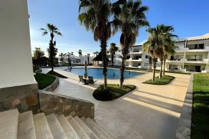 a swimming pool with palm trees and a building at Villa Dorada in Cabo San Lucas