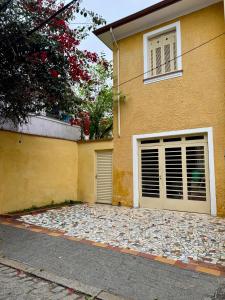 a house with two garage doors and a pile of rocks at Suíte charmosa com banheiro privativo, bairro tranquilo e arborizado, próximo ao metrô Ana Rosa e Avenida Paulista! in Sao Paulo