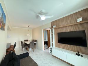 un salon avec une grande télévision à écran plat sur un mur dans l'établissement Apartamento Vista Mar Mirim 2 Dormitorios suite com Wifi para até 8 pessoas 1 vaga de estacionamento, à Praia Grande