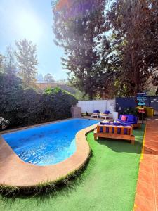 Una piscina con bancos y un patio de césped. en MAKTVB Costanera - Hostal Boutique, en Santiago