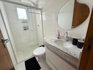 une salle de bain avec toilettes, lavabo et miroir dans l'établissement Apartamento Vista Mar Mirim 2 Dormitorios suite com Wifi para até 8 pessoas 1 vaga de estacionamento, à Praia Grande 11 autres photos