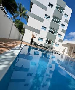 a man standing on the edge of a swimming pool in front of a building at Villa do Porto Resindece in Porto De Galinhas