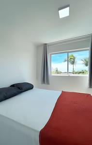 a bedroom with a bed and a window with a palm tree at Villa do Porto Resindece in Porto De Galinhas