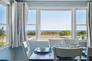 a dining room with a table and chairs and windows at Coastal Bliss in Rye