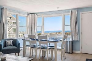 a dining room with a table and chairs and large windows at Coastal Bliss in Rye
