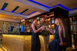Eine Gruppe von drei Personen steht in einer Bar in der Unterkunft Sandos Finisterra All Inclusive in Cabo San Lucas