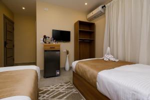 ein Hotelzimmer mit zwei Betten und einem Fernseher in der Unterkunft pyramids palace view iNN in Kairo