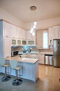 een keuken met witte kasten en een eiland met barkrukken bij Voula's Traditional House in Meyisti