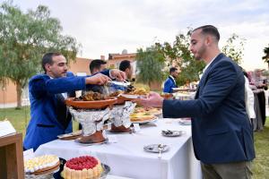 a group of men reaching for a plate of food on a table at Domaine Bahi - Marrakech in Marrakesh