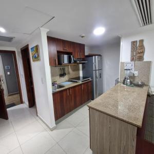 a kitchen with wooden cabinets and a stainless steel refrigerator at Vista al faro Habitacion doble in Guayaquil