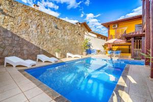 a swimming pool in front of a stone wall at Aldeia Da Lagoinha in Ubatuba