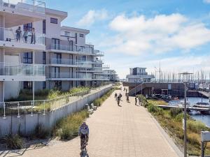 a group of people riding bikes on a sidewalk next to a building at Moderne Ferienwohnung direkt am Meer in Wendtorf