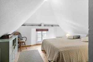 a white bedroom with a bed and a chair at 10090-Ulfborg-Baekbyvej-82 in Øhuse