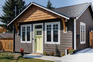 a tiny house with a yellow door and a fence at Brass Apple Cottage in Campbell River