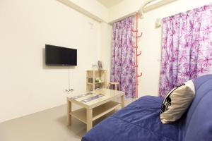 Cette chambre dispose d'un canapé, d'une table et d'une télévision. dans l'établissement B-wei B&B, à Hualien