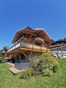 una grande casa in legno con terrazza su un campo di Chalet Le M - Adults only - Standing - Samoëns Grand-Massif a Samoëns