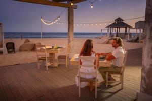 Ein Mann und eine Frau sitzen an einem Tisch am Strand in der Unterkunft Sandos Finisterra All Inclusive in Cabo San Lucas