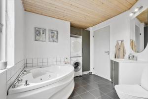 een badkamer met een wit bad en een wasmachine bij 60836-Ulfborg-Fjand-Strand-29 in Fjand Gårde +25 foto's