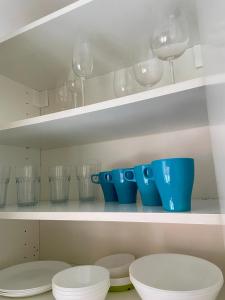 a shelf with cups and plates and wine glasses at Lelle Stay in Kuldīga