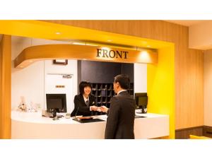宇都宮市にあるSmile Hotel Utsunomiya Higashiguchi - Vacation STAY 12713vのオフィスの受付に立っている二人