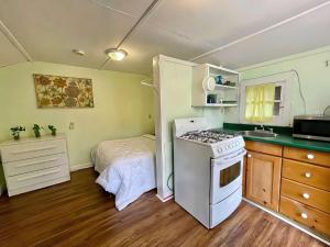 cocina pequeña con fogones y cama en Ambleside - 1-Bedroom Cottage #3, en Kawartha Lakes