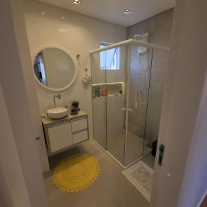 a bathroom with a shower and a sink and a mirror at Apartamento moderno com suíte e garagem a 500 m da praia in Balneário Camboriú +4 photos