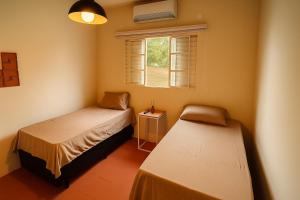 a bedroom with two beds and a window at Chalé Roberta in Holambra