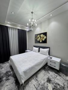 a bedroom with a large white bed and a chandelier at Anisa guest house in Samarkand