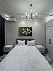 a bedroom with a large white bed with a chandelier at Anisa guest house in Samarkand