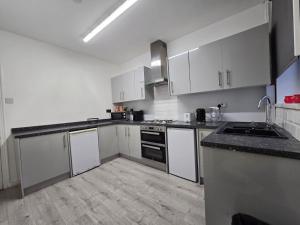 a kitchen with white cabinets and black counter tops at Room 2 shared house 5 minutes from Anfield in Liverpool