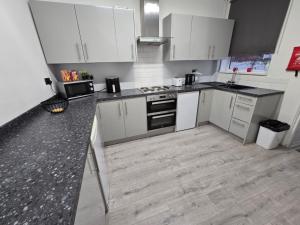 a kitchen with white cabinets and a wooden floor at Room 2 shared house 5 minutes from Anfield in Liverpool +21 photos