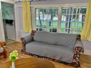 3-Bedroom Cottage #7 - Ambleside في كاوارثا ليك: أريكة للجلوس في غرفة المعيشة مع نوافذ